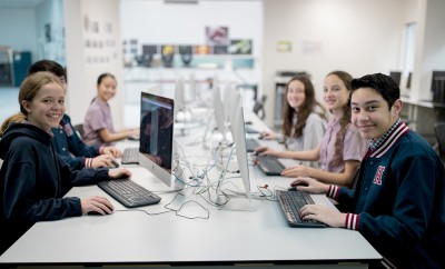 Students smiling while sitting in front of computers